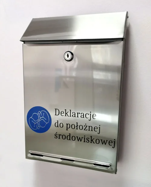 Metalowa skrzynka na deklaracje z napisem „Deklaracje do położnej środowiskowej”, zamontowana na ścianie przy wejściu do poradni